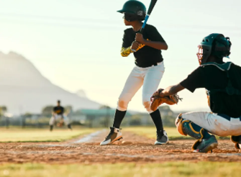 Un battitore della Ottawa Sports Academy Private School impugna una mazza sul campo da baseball accanto a un ricevitore.