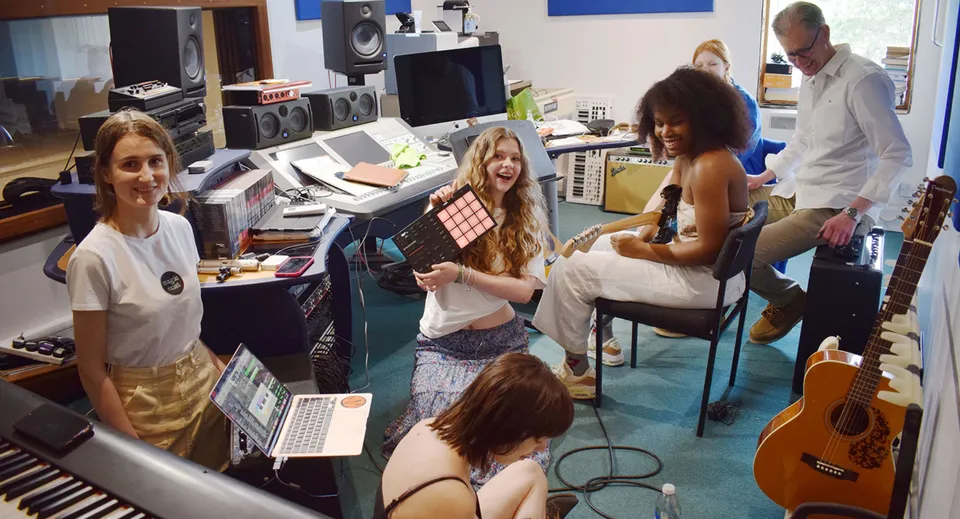 Un gruppo di studenti e studentesse della Bedales School lavora insieme in uno studio musicale con vari strumenti e attrezzature tecniche.