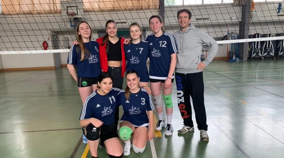 La squadra di pallavolo del Lycée Gabriel Fauré posa insieme in una palestra con un canestro da basket visibile.