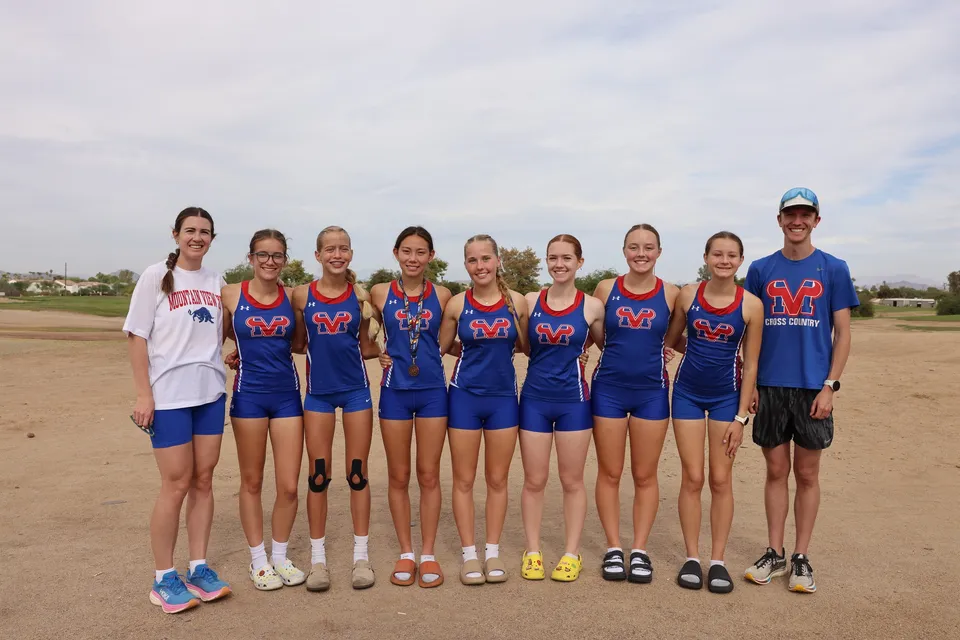 Un gruppo di giovani atlete della Mountain View High School si trova su un campo sportivo sotto un cielo nuvoloso.