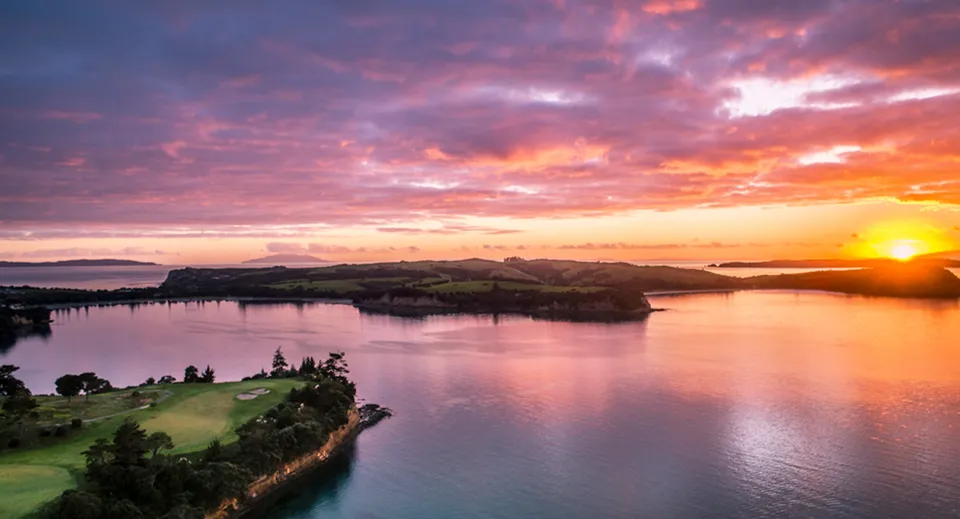 Il tramonto su un lago calmo con colline verdi vicino al Wentworth College.