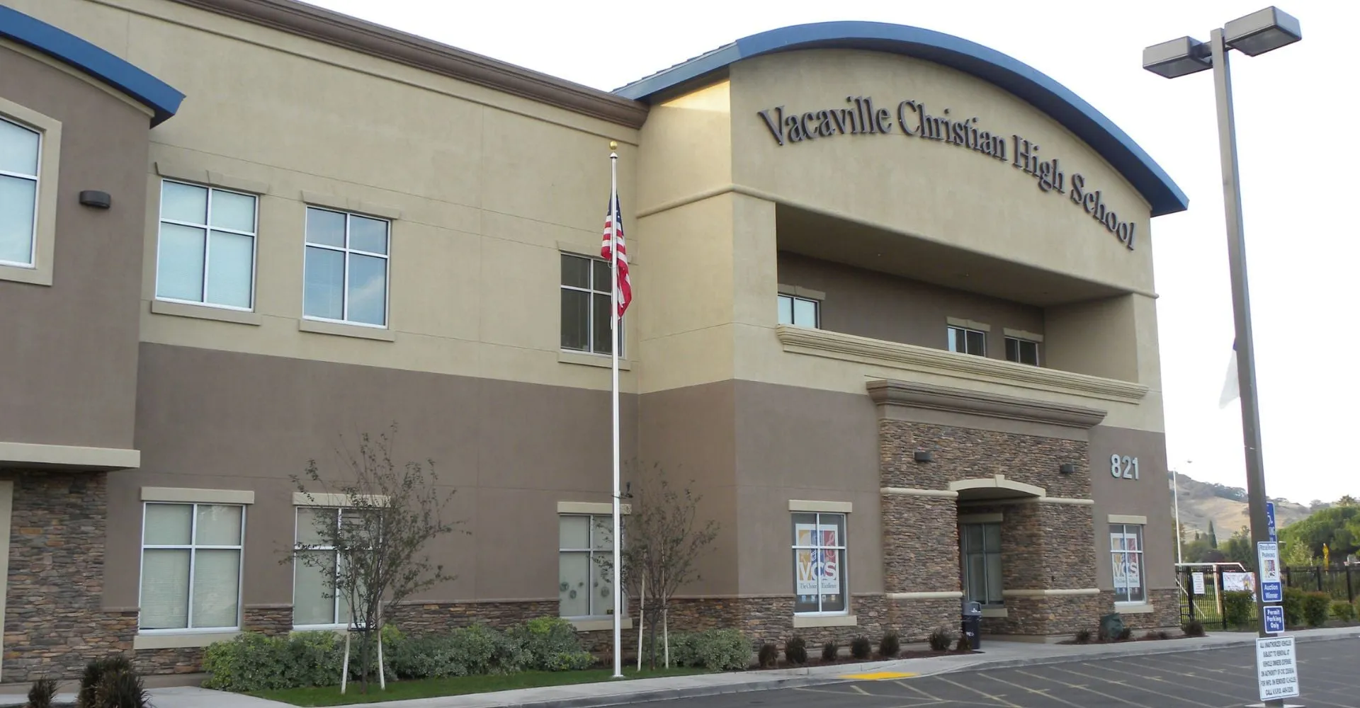 L'edificio a più piani della Vacaville Christian School è visibile con un'insegna sulla facciata e una cura del paesaggio ben visibile in primo piano.