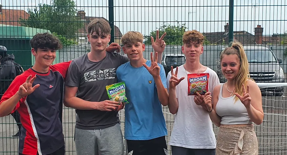 Un gruppo di studenti e studentesse sta davanti a una recinzione nel campus del Salisbury Sixth Form College.