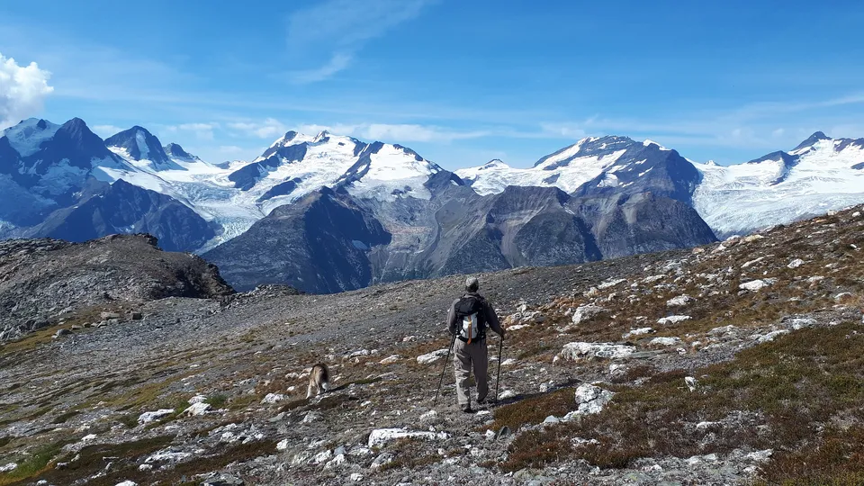 Una persona si trova su un sentiero roccioso con montagne innevate sullo sfondo nel campus della Thomas Haney Secondary School.