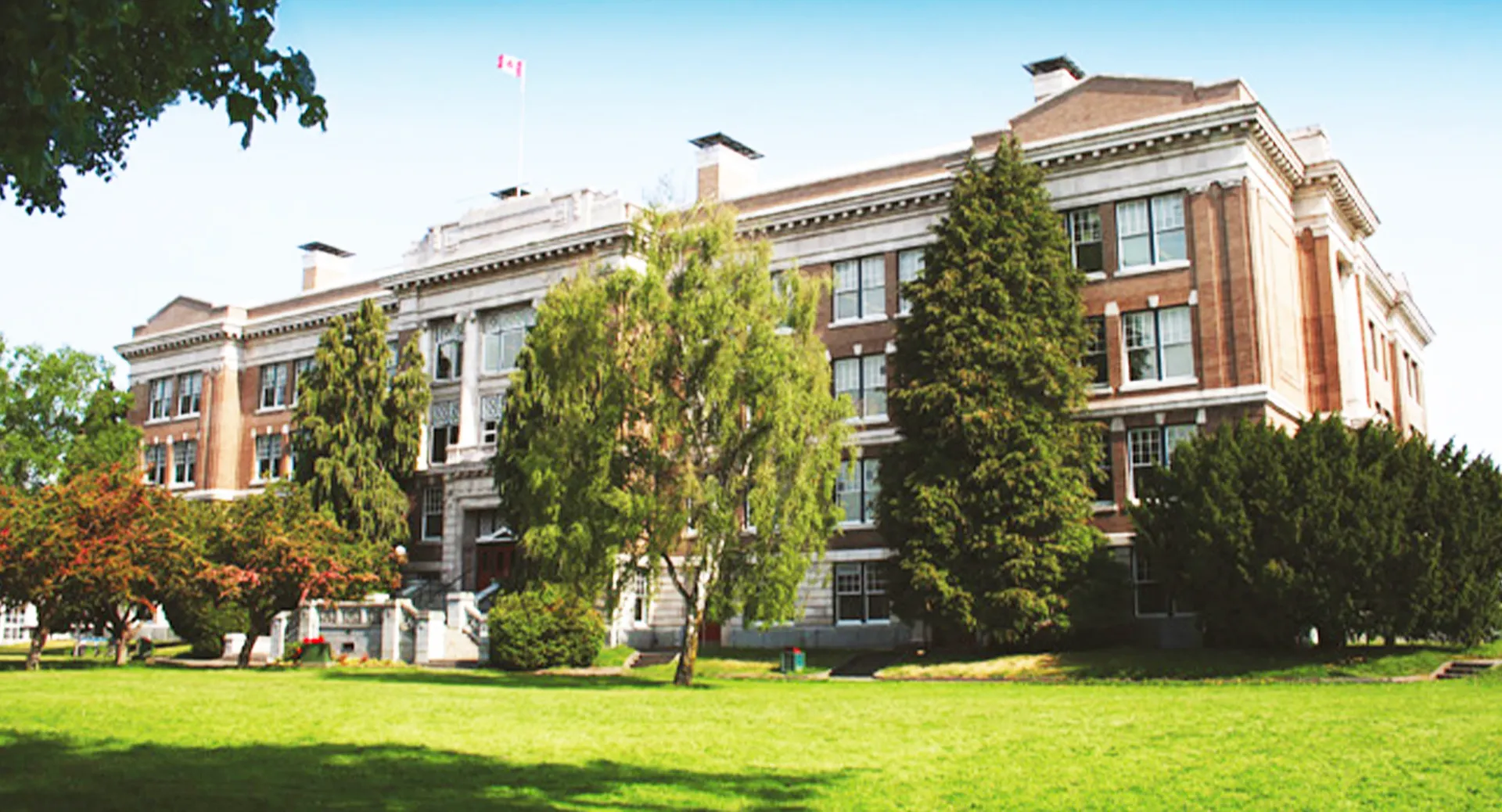 L'edificio storico in mattoni della Victoria High School si trova su un prato verde circondato da alberi.