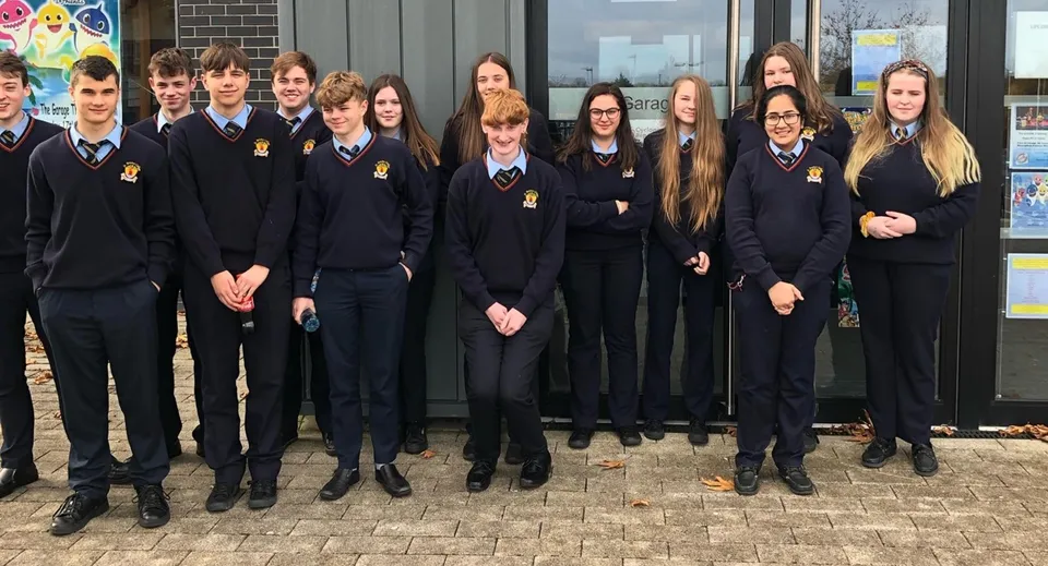 Un gruppo di studenti e studentesse della Cabinteely Community School si trova davanti a un edificio in mattoni.