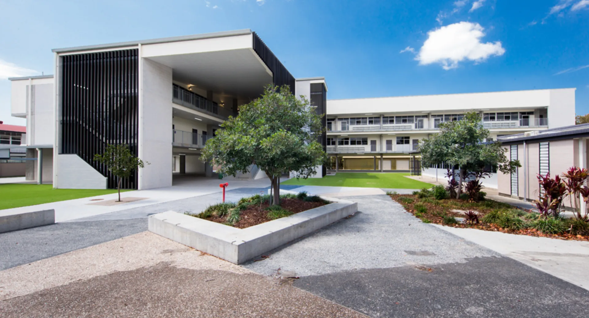 L'edificio scolastico moderno a più piani della Palm Beach Currumbin State High School è circondato da alberi verdi.
