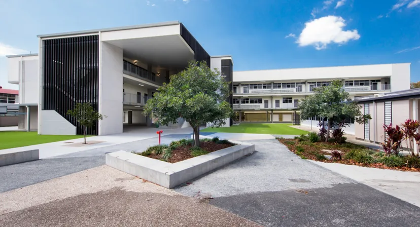 L'edificio scolastico moderno a più piani della Palm Beach Currumbin State High School è circondato da alberi verdi.