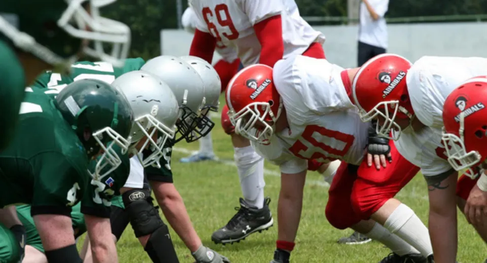 Gli studenti del Silverthorn Collegiate Institute sono sul campo da calcio con maglie rosse e bianche di fronte ai loro avversari con maglie verdi e bianche.