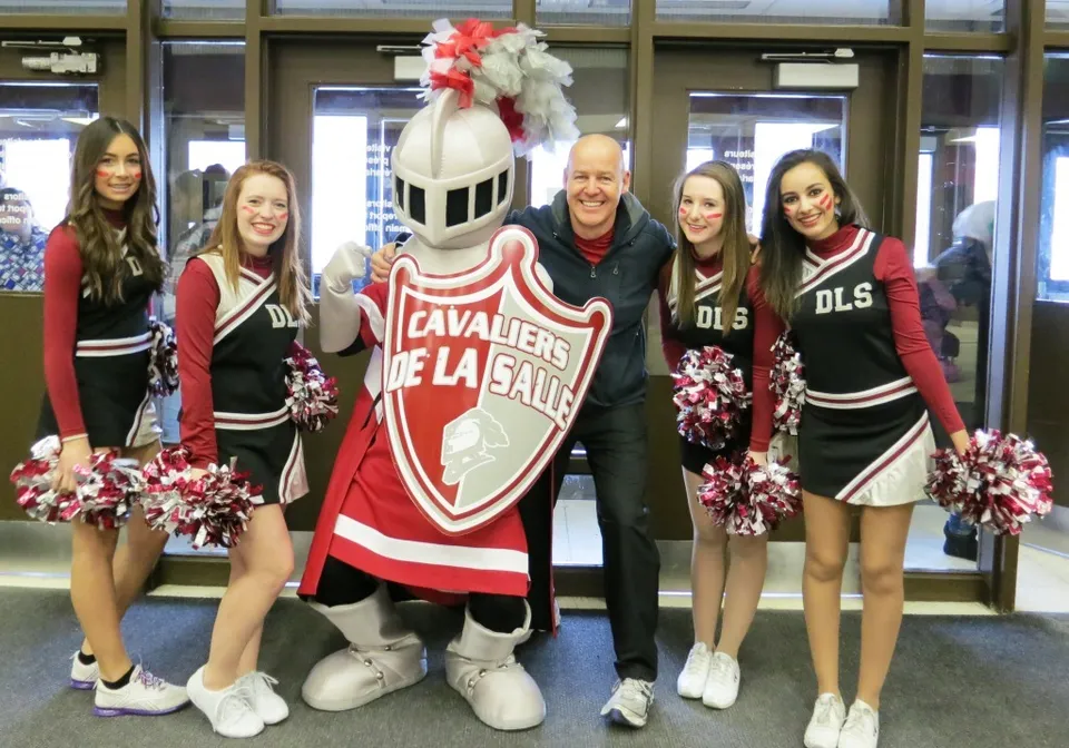 Cheerleader e mascotte posano insieme in rosso e nero sul campus della École secondaire publique De La Salle.