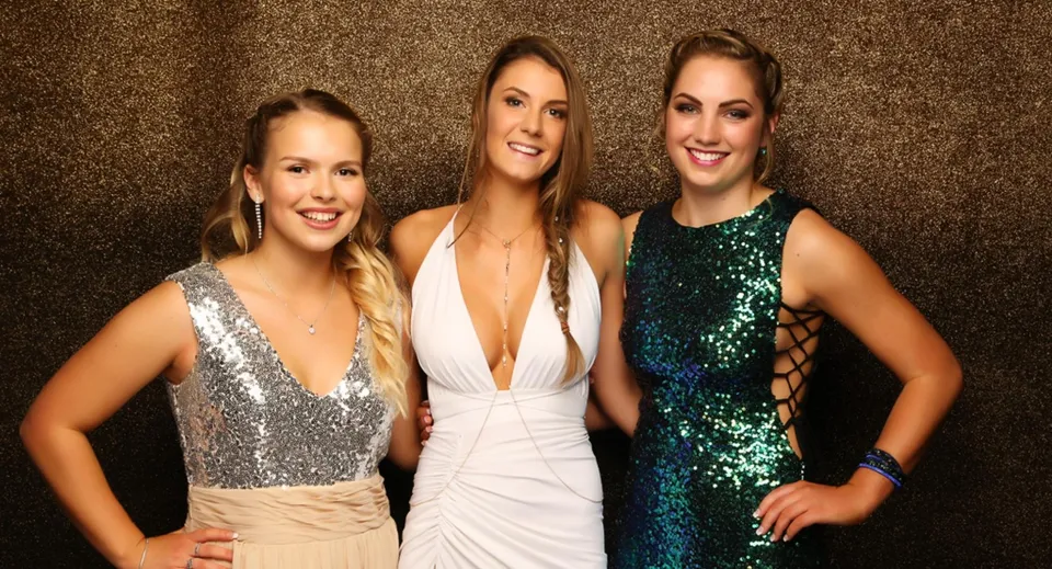 Tre studentesse del St. Dominic's Girl’s Catholic College posano insieme davanti a uno sfondo scuro.