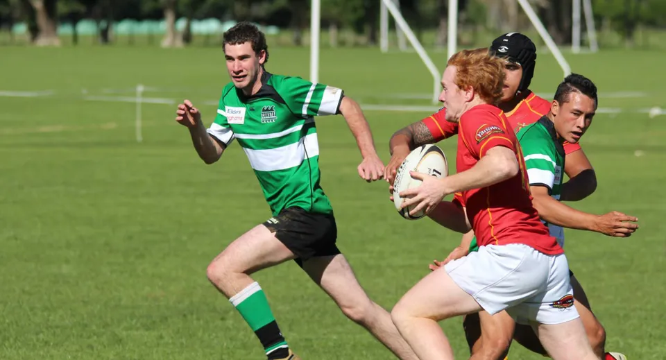 Due giocatori di rugby sul campo del Francis Douglas Memorial College sono impegnati in un contrasto durante una partita.