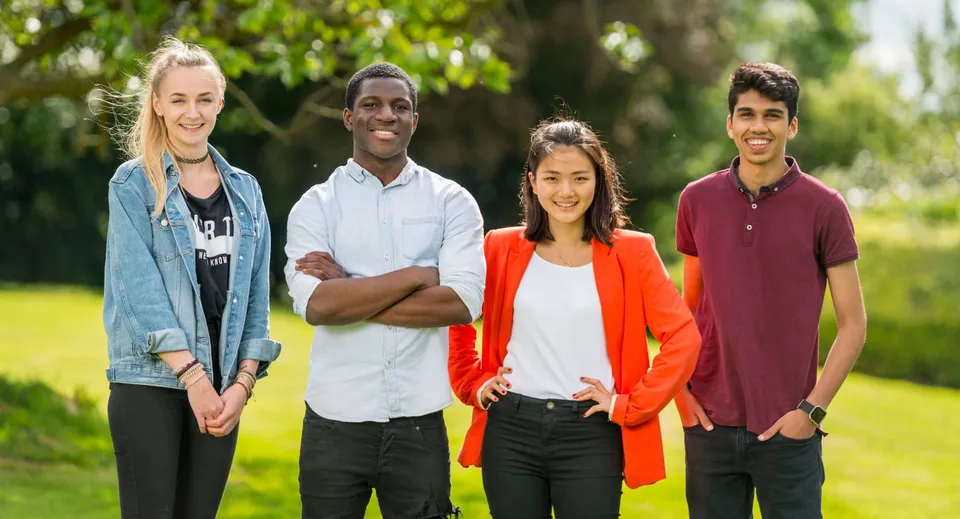 Cuatro estudiantes están juntos en un área verde en el campus de Padworth College.