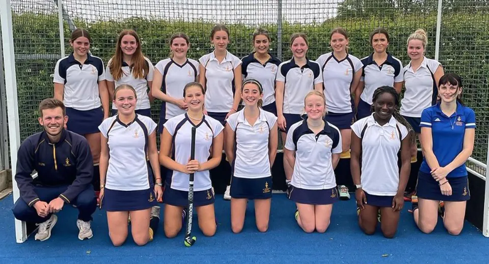Un gruppo di giovani atlete posa sul campo sportivo della St Edward's School a Oxford davanti a una rete metallica.