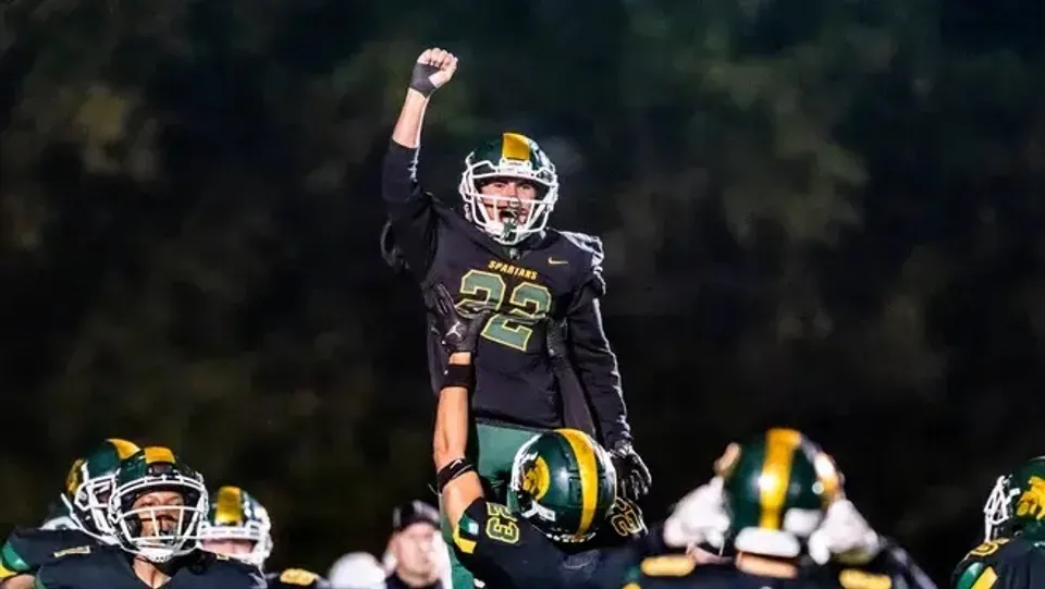 Un giocatore di football della Martin Luther High School con il numero 22 festeggia sul campo con i suoi compagni di squadra.