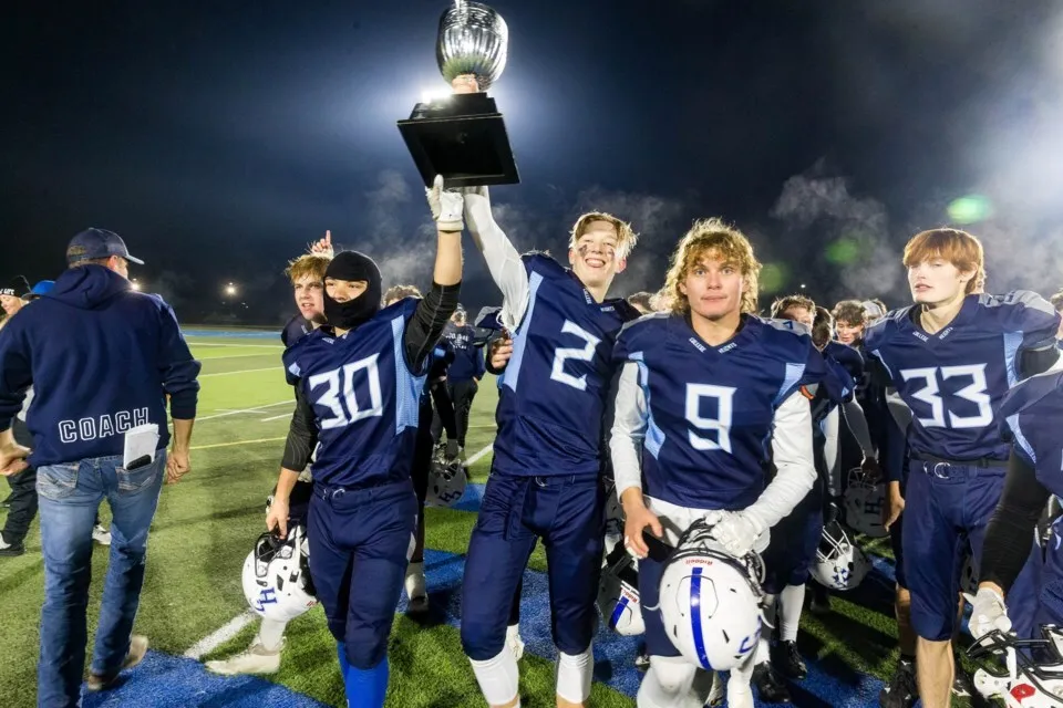 I giocatori di football della College Heights Secondary School festeggiano la loro vittoria sollevando un trofeo sul campo.
