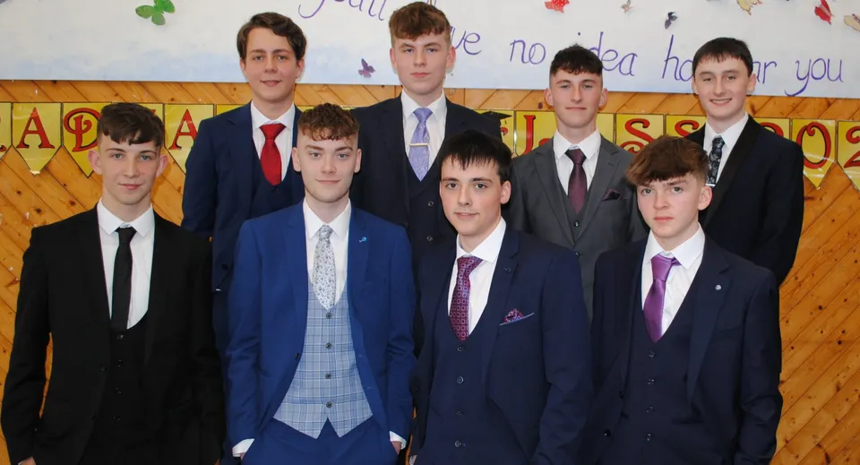 Un gruppo di studenti della Christian Brothers School Kilkenny sta in abito formale davanti allo sfondo di un'aula colorata.