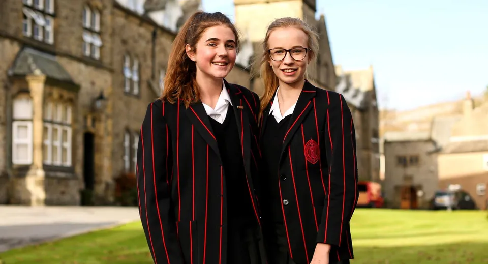 Due studentesse in stile Hogwarts si trovano insieme nel campus della Giggleswick School.