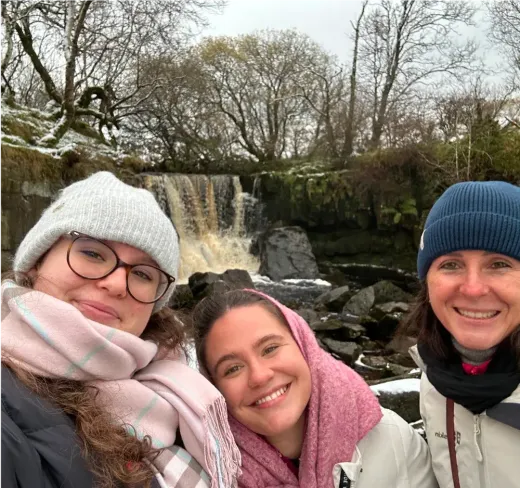 Drei Mädchen machen im Winter ein Selfie vor einem Wasserfall in Irland