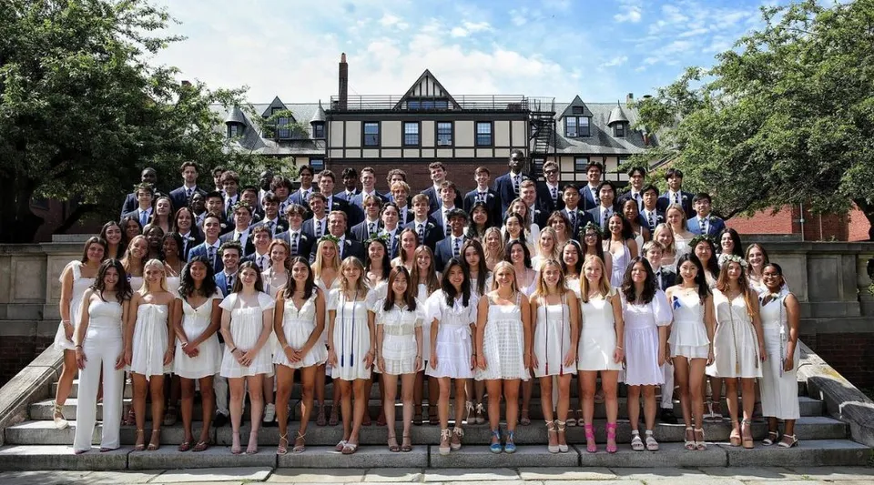 Un grande gruppo di studenti della St. Mark's School posa in abiti eleganti su una scalinata davanti all'edificio scolastico.