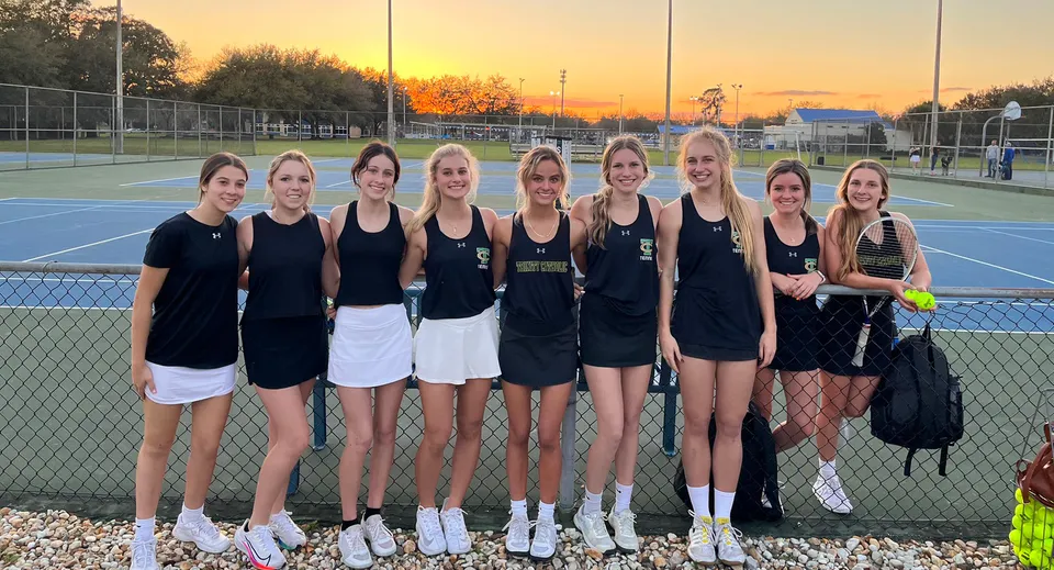 Un gruppo di giovani tenniste posa sul campo da tennis della Trinity Catholic High School al tramonto.