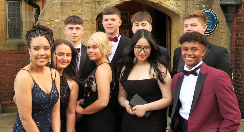 Un gruppo di studenti del Tettenhall College in abiti formali posa davanti a un edificio storico con archi a tutto sesto.