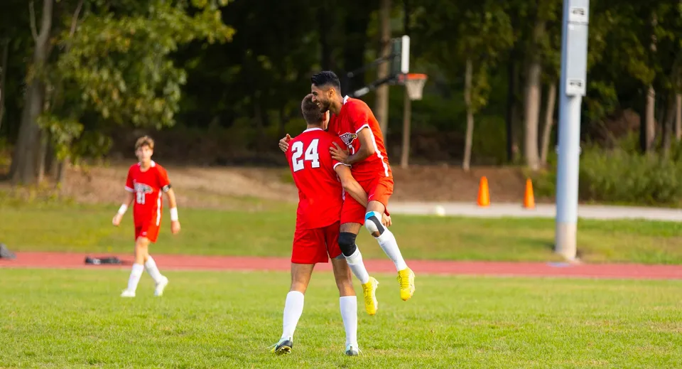 Due giocatori di calcio in maglia rossa giocano sul campo sportivo della The Knox School.