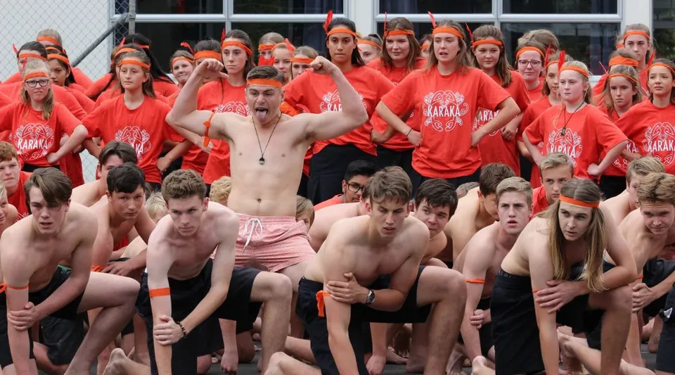 Un gruppo di studenti del Mahurangi College indossa maglie rosse e si raduna all'aperto.