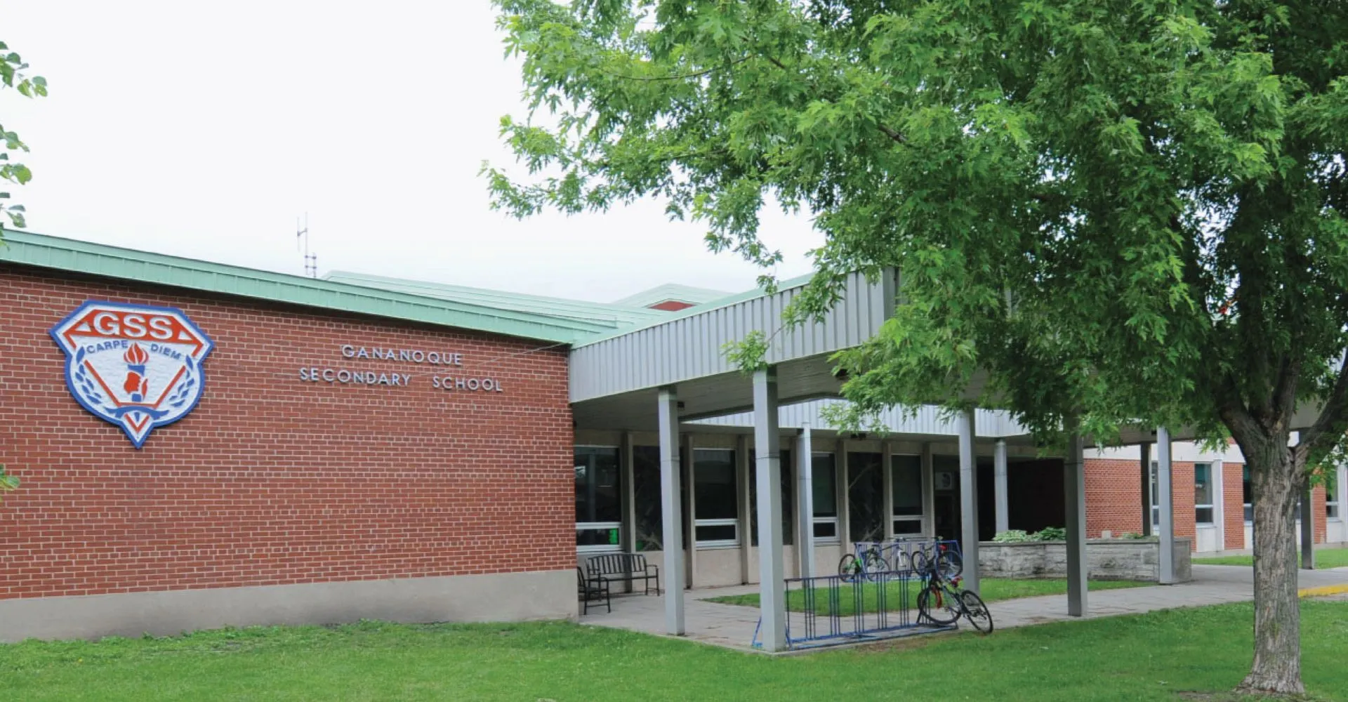 L'edificio in mattoni della Gananoque Secondary School è circondato da alberi verdi e da un prato.