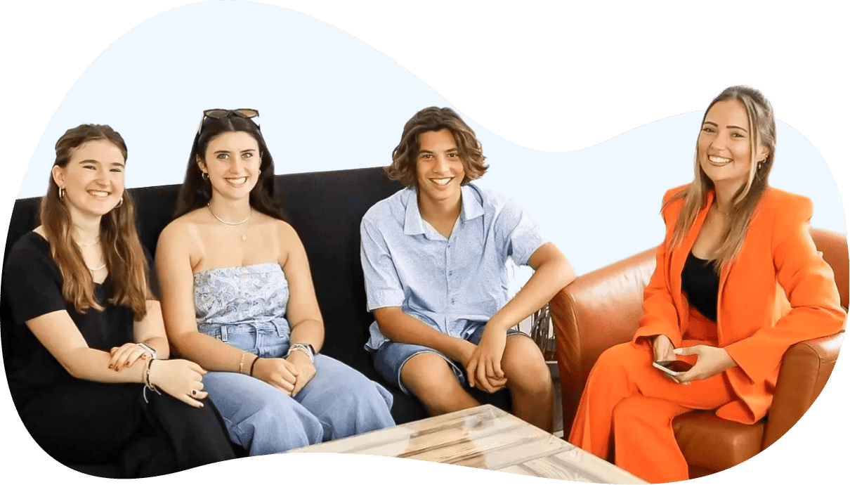 Vier junge Austauschschülerinnen und Austauschschüler sitzen lachend nebeneinander auf einem Sofa