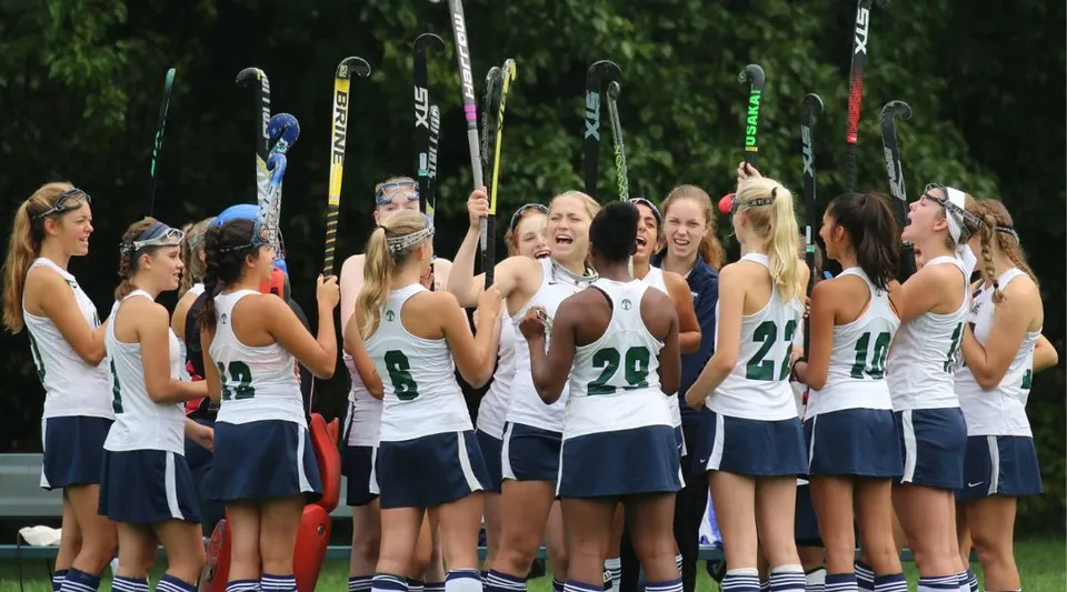 Un gruppo di giovani tenniste della Cranbrook Schools è insieme sul campo da tennis con le racchette da tennis sullo sfondo.
