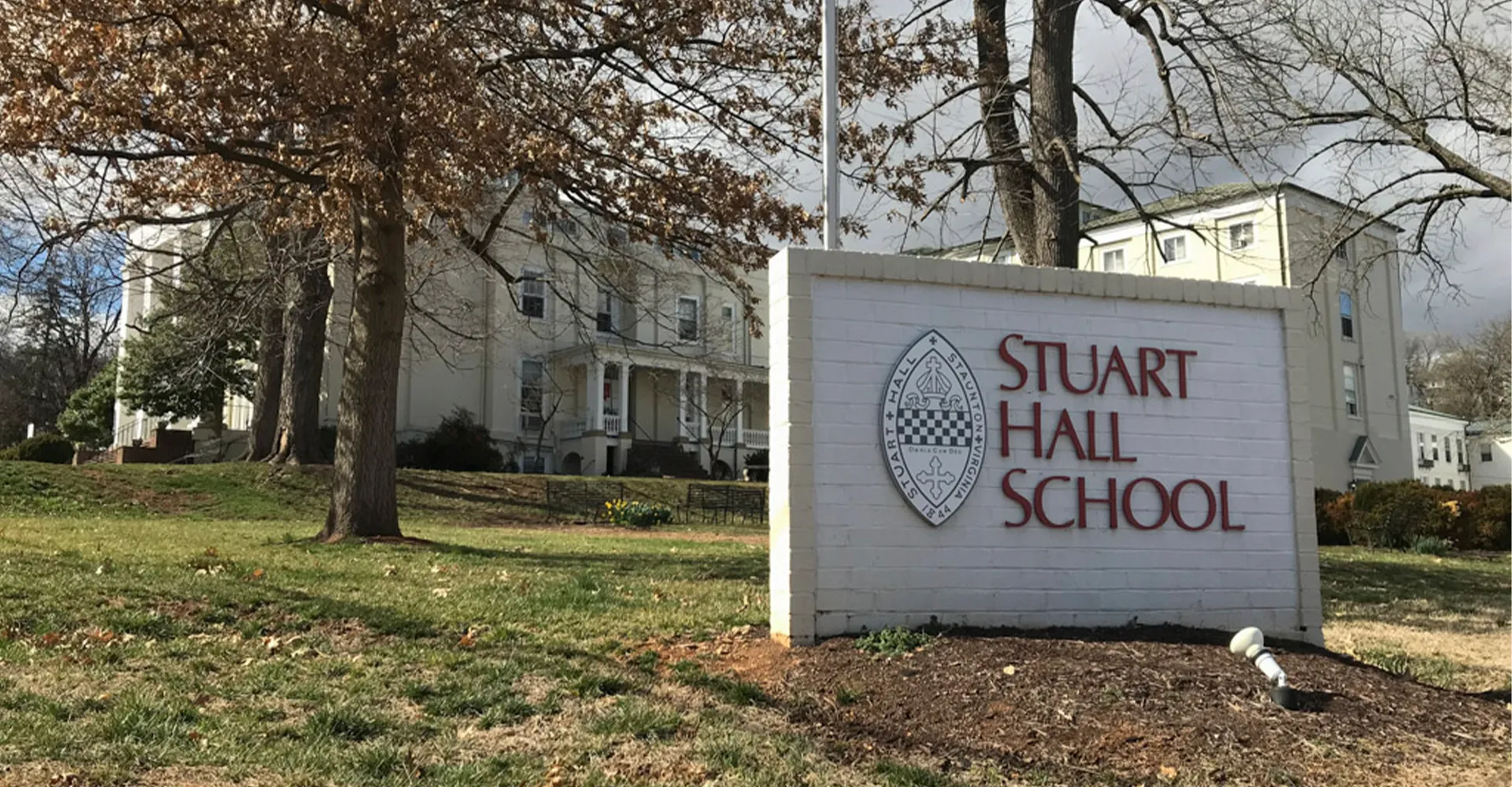 L'edificio con la facciata bianca e l'insegna della Stuart Hall School sono circondati da alberi.