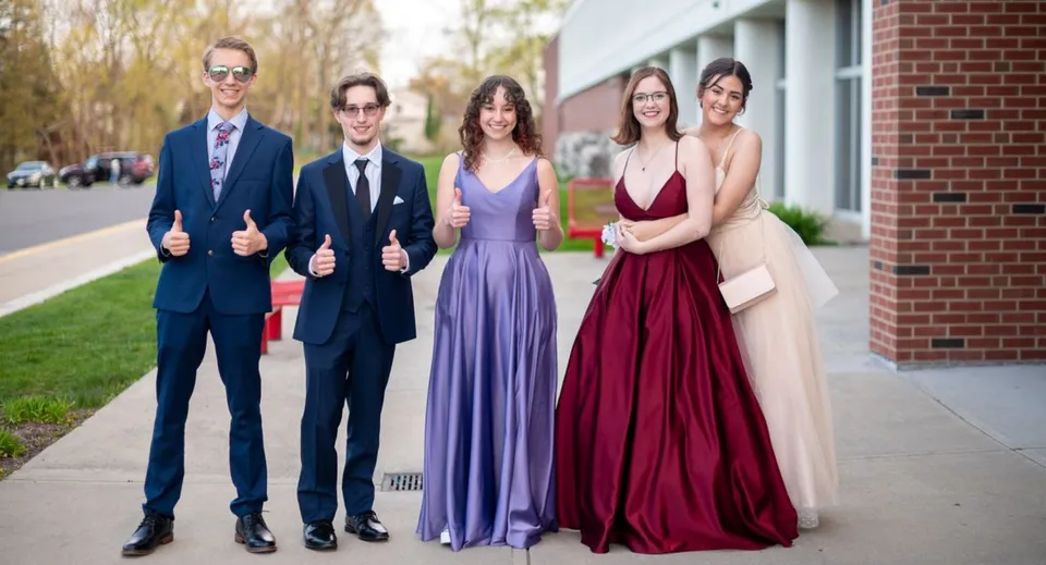 Un gruppo di persone si trova nel campus della JSerra Catholic High School davanti a un edificio in mattoni.