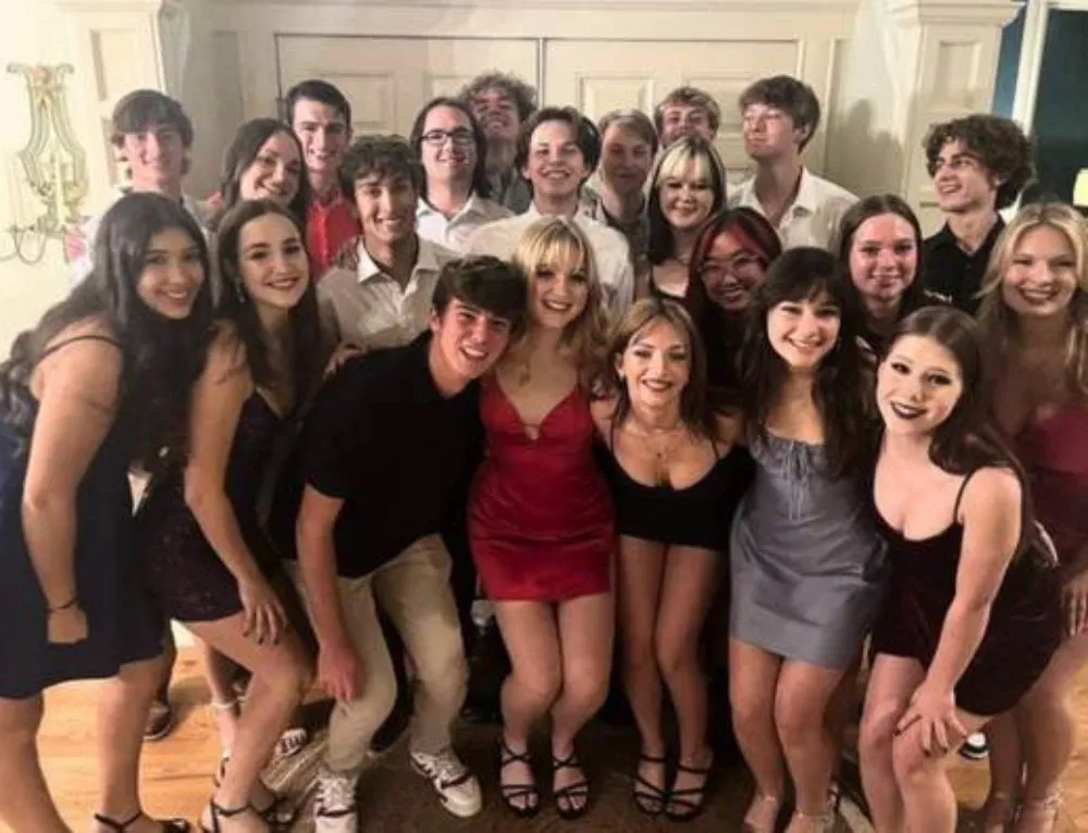 Grupo de jóvenes vestidos elegantes posando juntos y sonrientes dentro de una vivienda