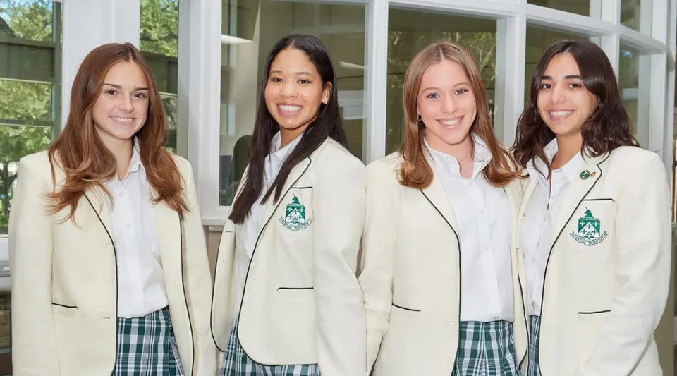 Quattro studentesse di The Hockaday School sono in piedi davanti a un edificio con ampie finestre.