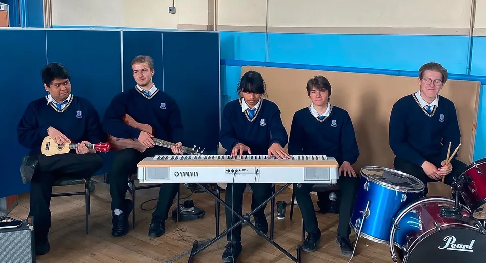 Studenti del Marian College suonano diversi strumenti musicali come la tastiera e la batteria all'interno dell'edificio scolastico.