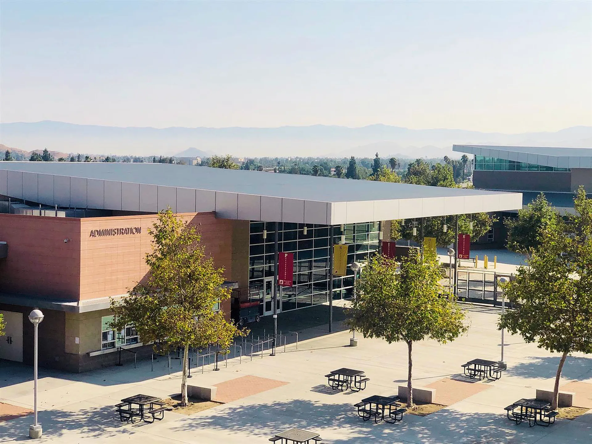 L'edificio moderno a più piani con pareti in vetro del Bonneville Joint School District è circondato da alberi e mostra le montagne sullo sfondo.