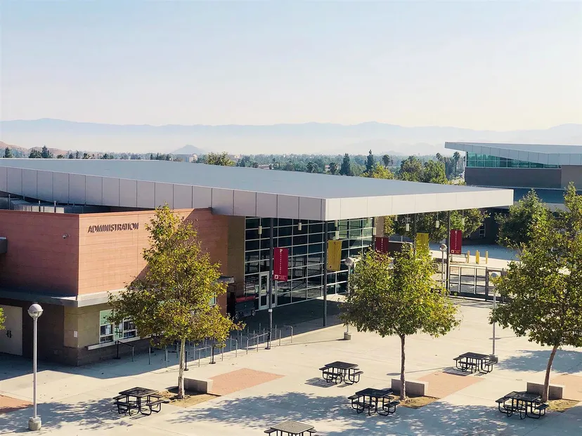 L'edificio moderno a più piani con pareti in vetro del Bonneville Joint School District è circondato da alberi e mostra le montagne sullo sfondo.