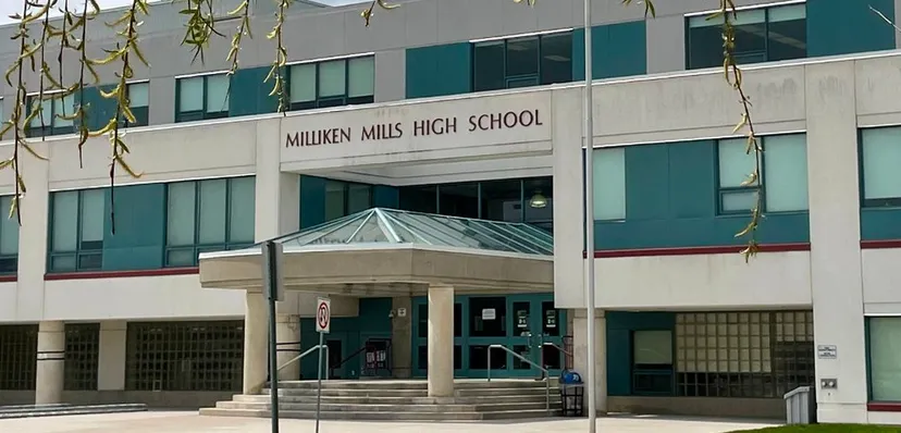 L'ingresso del moderno edificio della Milliken Mills Secondary School è realizzato in vetro e cemento ed è circondato da piante pendenti.