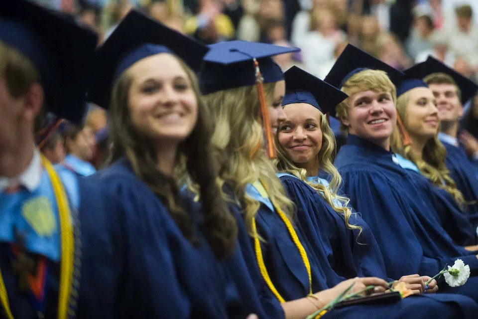 Neodiplomati e neodiplomate della Catholic Central High School posano insieme in gruppo con le loro toghe blu e gialle.