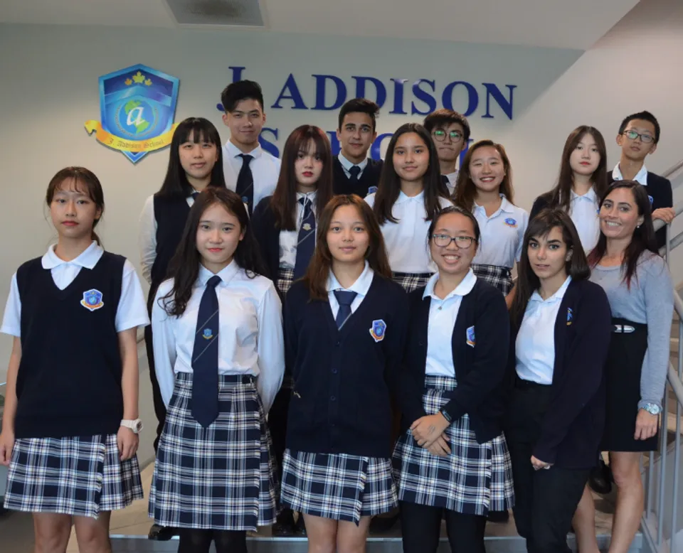 Un gruppo di studenti della J. Addison School posa davanti a uno sfondo con il nome e il logo della scuola.
