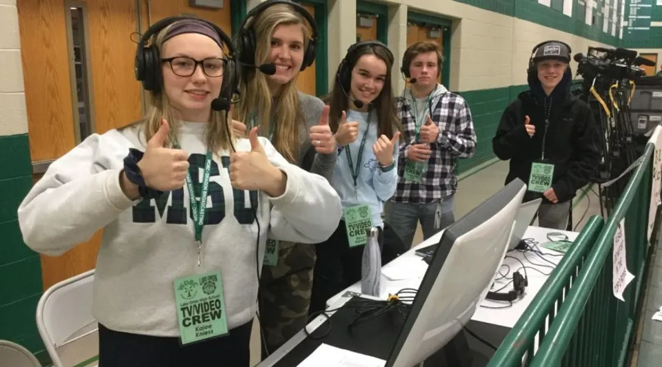 Studenti della Lake Orion High School sono in piedi nel corridoio con pareti verdi e armadietti.