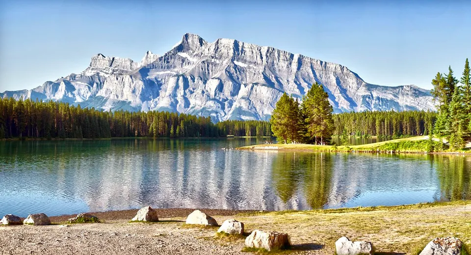 Un tranquillo lago di montagna con cime innevate e sponda boscosa vicino alla Mount Boucherie Secondary School.