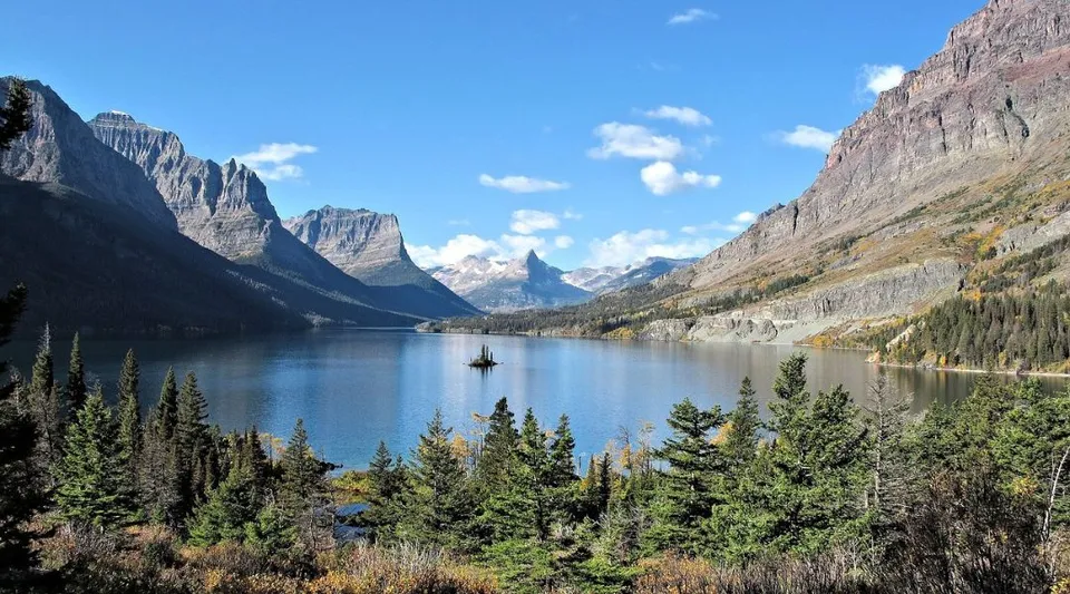 Un tranquillo lago di montagna con una piccola barca e abeti sulla riva nell'area della St. Timothy High School.