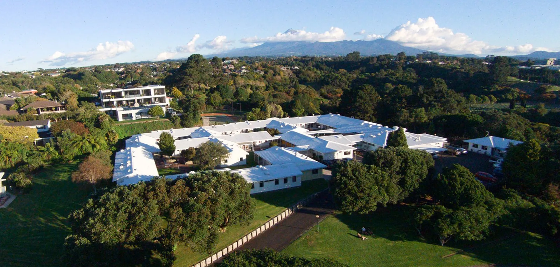 L'area esterna della New Plymouth Girls’ High School mostra un'ampia zona residenziale immersa nel verde con montagne sullo sfondo.