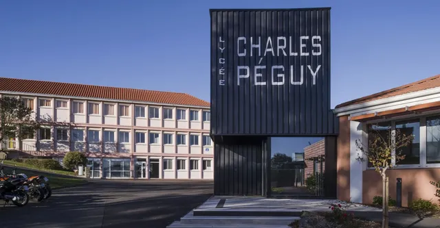 Grande struttura nera con la scritta Charles Péguy davanti a edifici moderni nel campus del Lycée Charles Péguy.