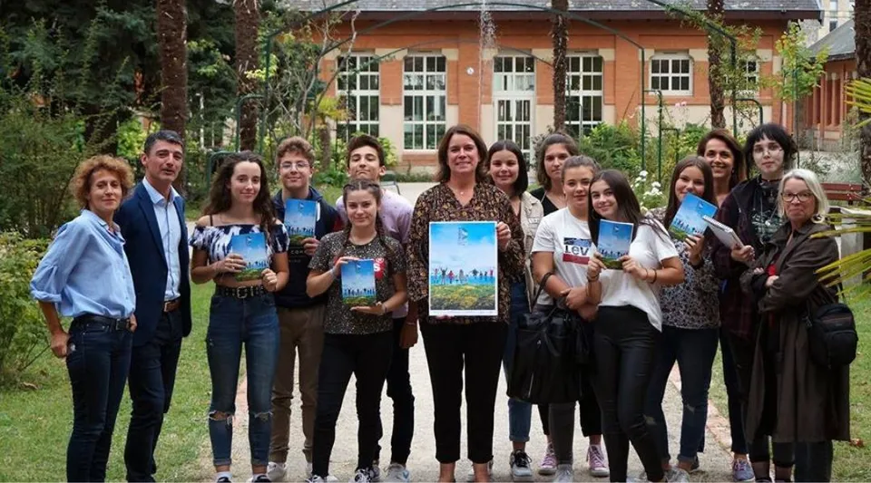 Un gruppo di studenti e studentesse si trova all'esterno dell'edificio del Lycée Gabriel Fauré con un dipinto esposto.