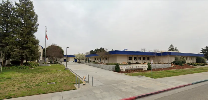 L'edificio della Clovis High School con finiture blu sul tetto, un'insegna con il nome della scuola e un pennone con la bandiera.