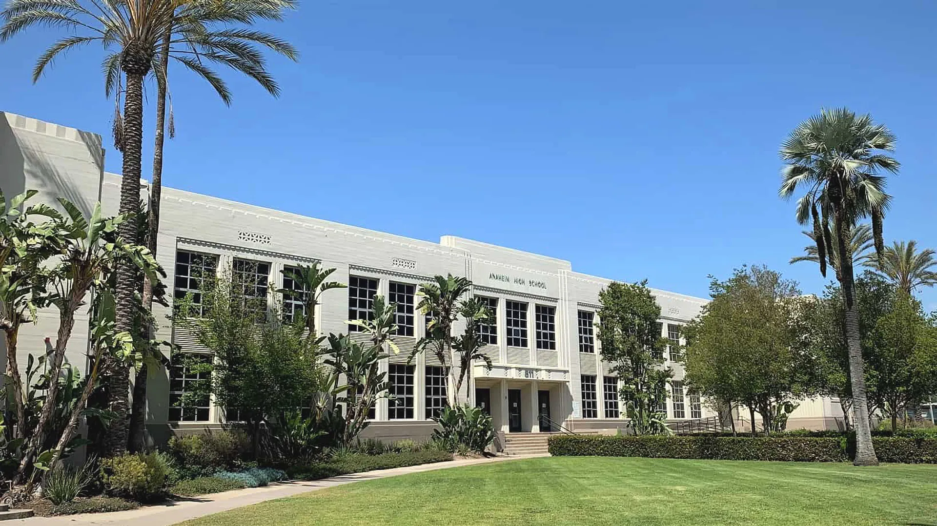 L'edificio bianco a più piani con finestre ad arco dell'Anaheim Union High School District davanti a palme e a un cielo blu.