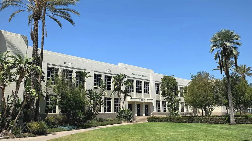 L'edificio bianco a più piani con finestre ad arco dell'Anaheim Union High School District davanti a palme e a un cielo blu.